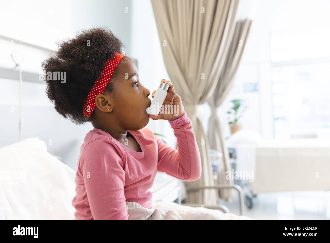 African american girl patient sitting on bed using inhaler at hospital ...