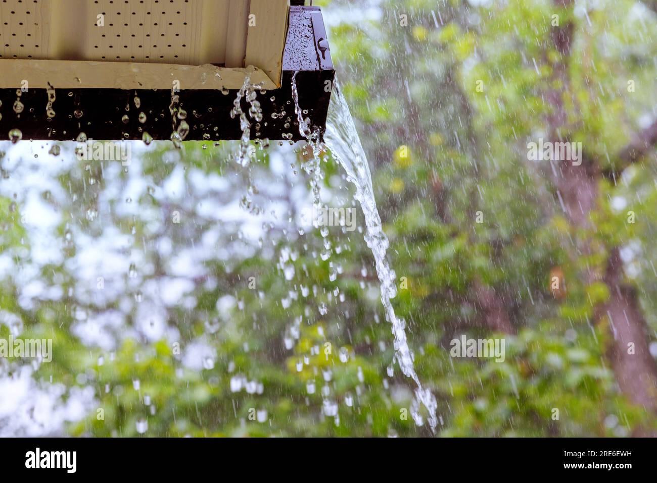 During heavy rain, water cascades from overflowing gutters Stock Photo