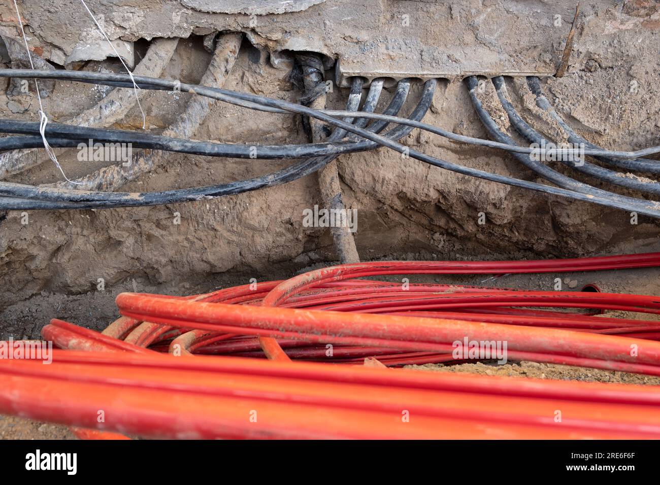 Electric cables in red corrugated pipe are buried underground on the