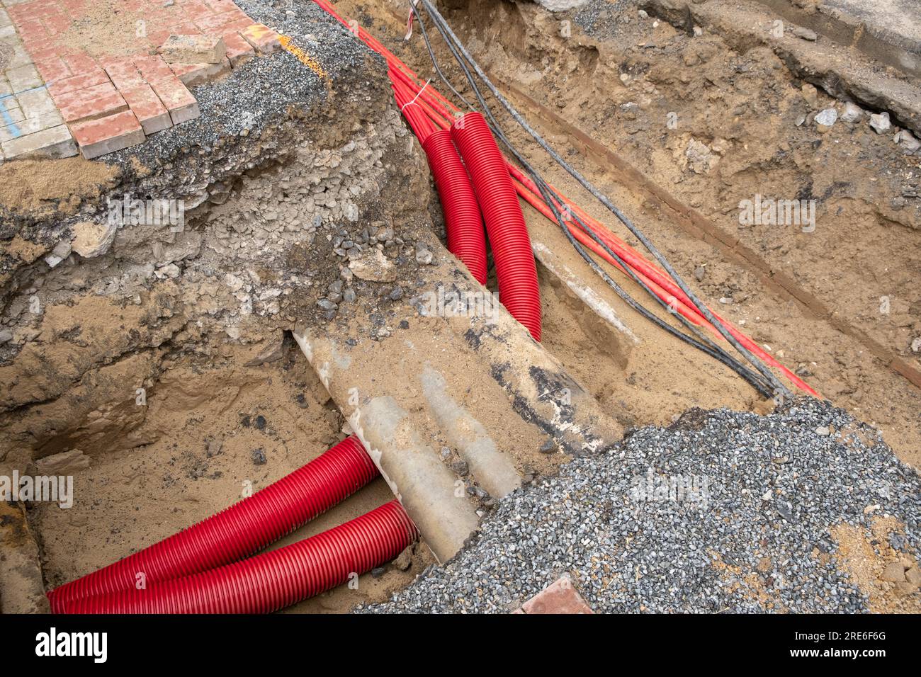 Electric cables in red corrugated pipe are buried underground on the