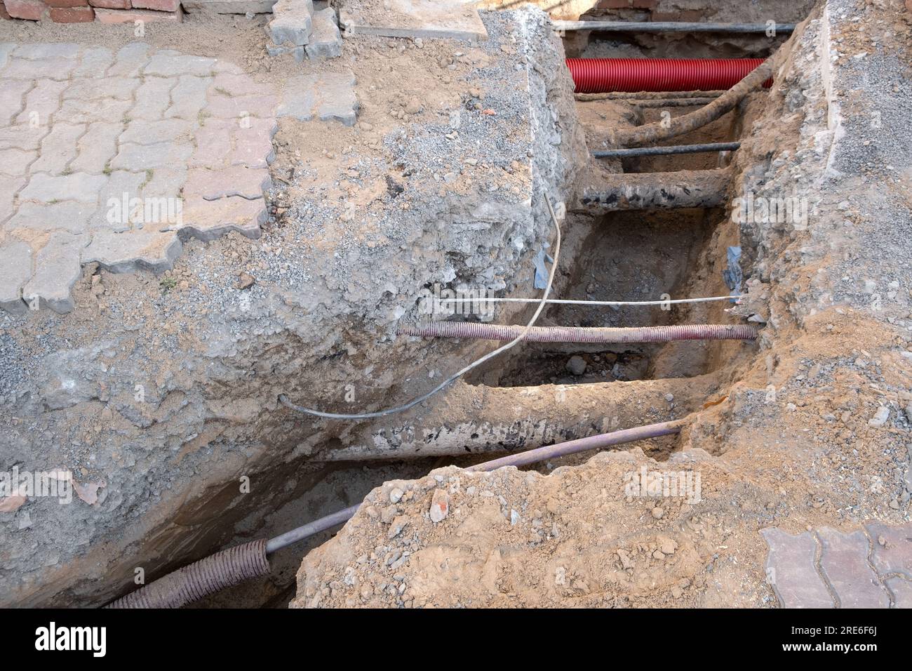Electric cables in red corrugated pipe are buried underground on the