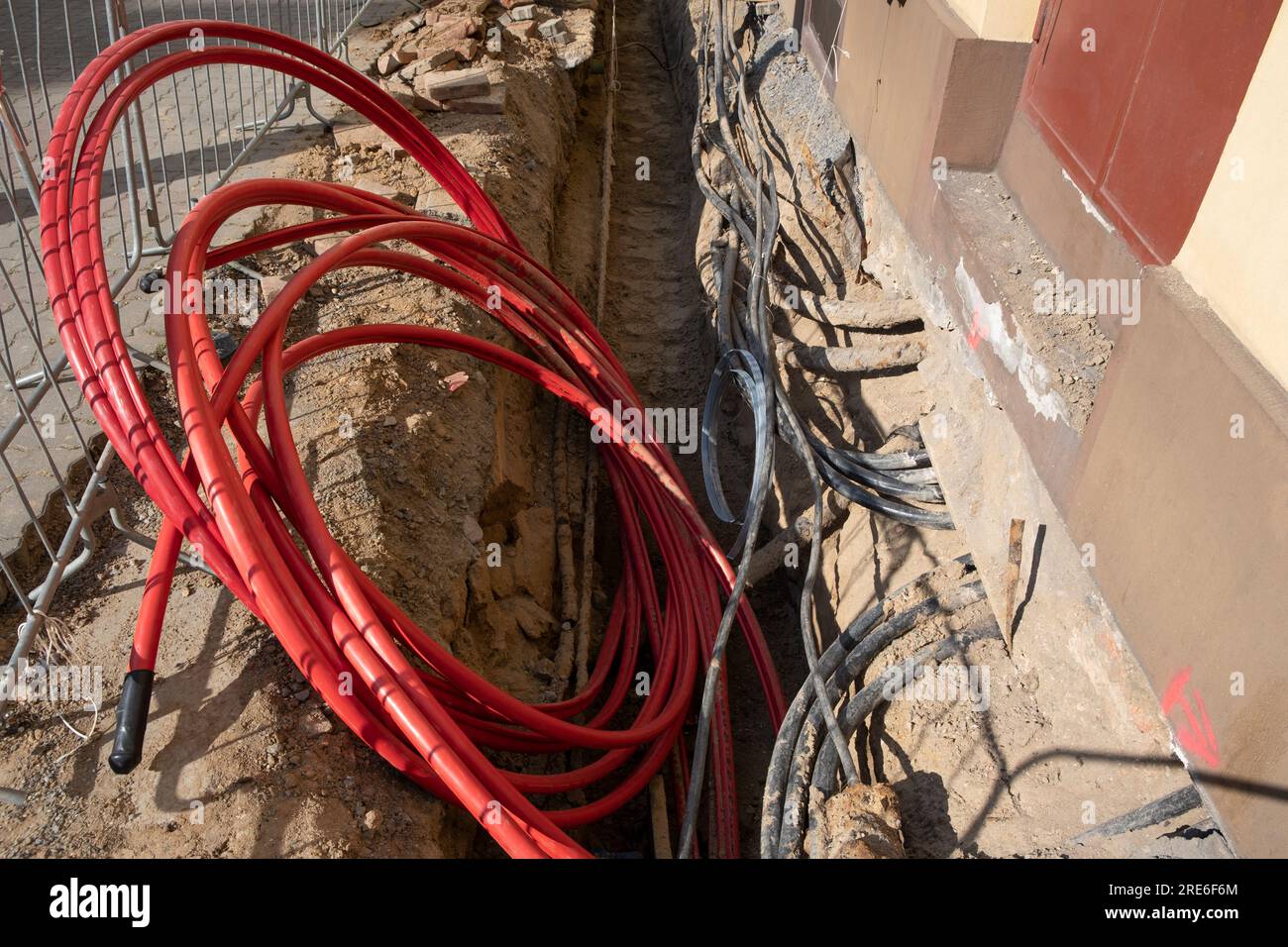 Electric cables in red corrugated pipe are buried underground on the