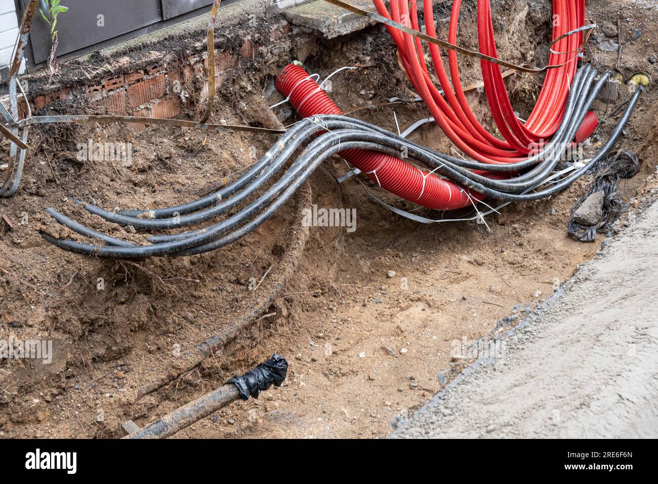 Electric cables in red corrugated pipe are buried underground on the
