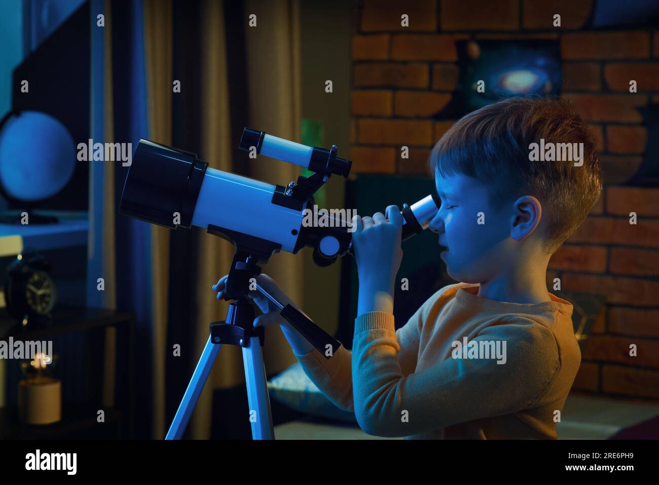 Little boy looking at stars through telescope in room Stock Photo Alamy