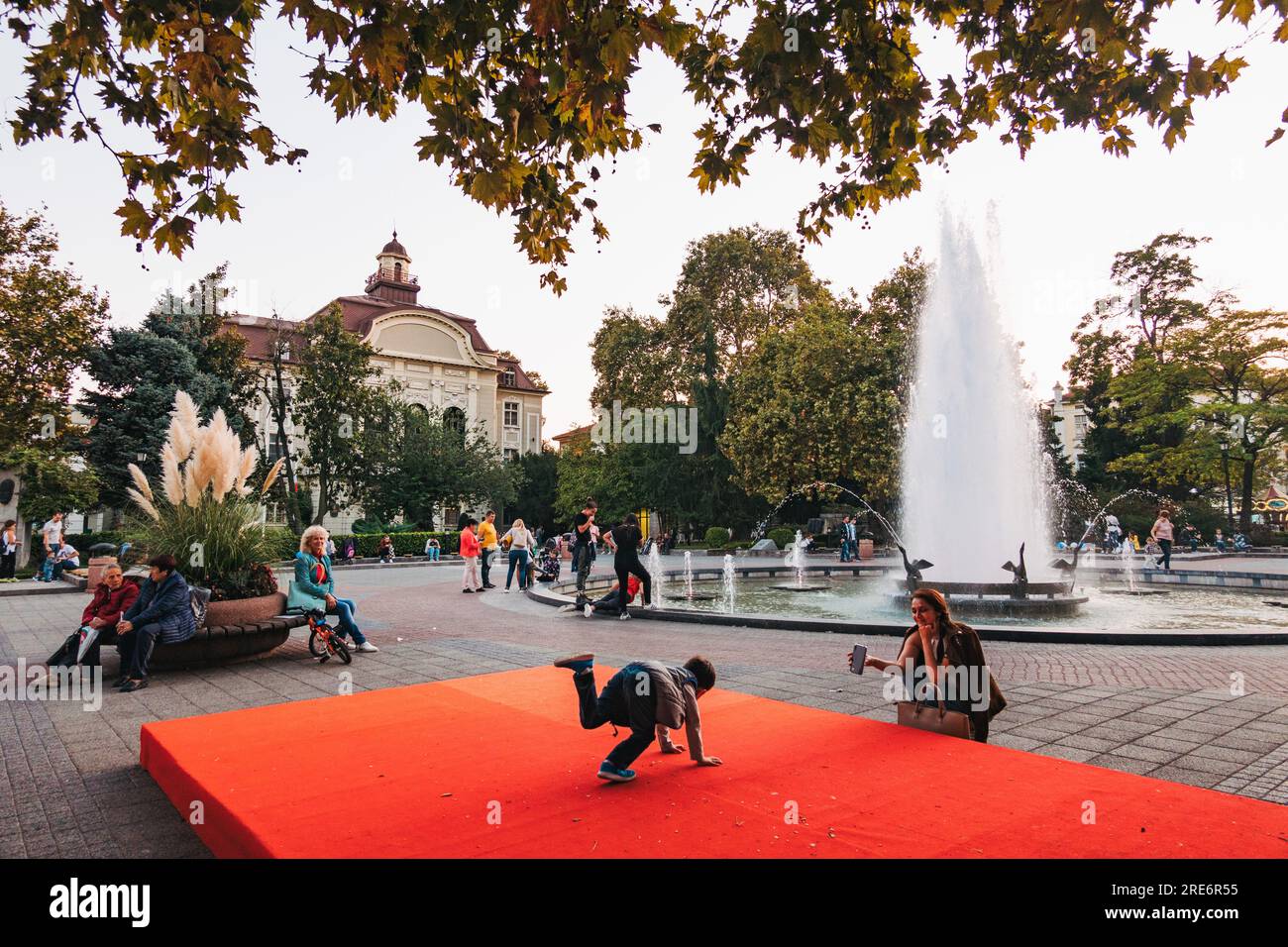 a kid plays on a red platform next to a fountain in the main street of Plovdiv, Bulgaria Stock Photo