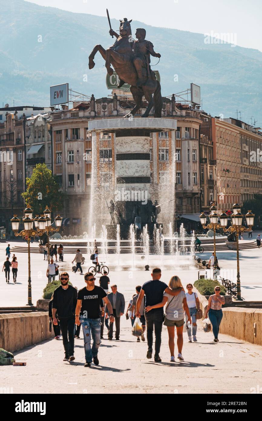 people walking in the main square of Skopje, North Macedonia. A sculpture of Alexander the Great is seen behind. Stock Photo