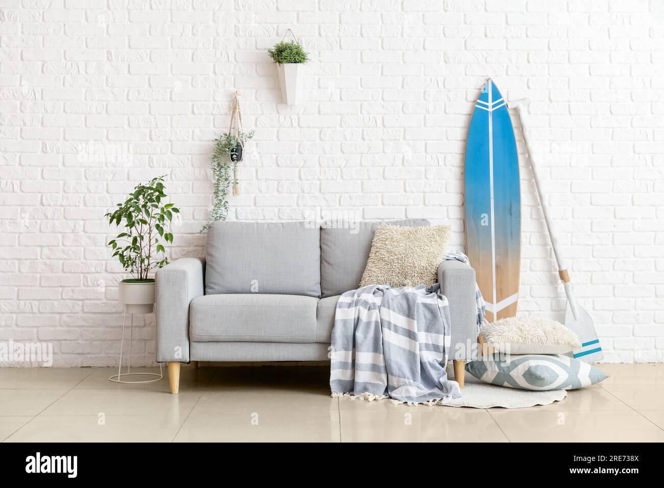 Interior of living room with surfboard, paddle and sofa Stock Photo - Alamy
