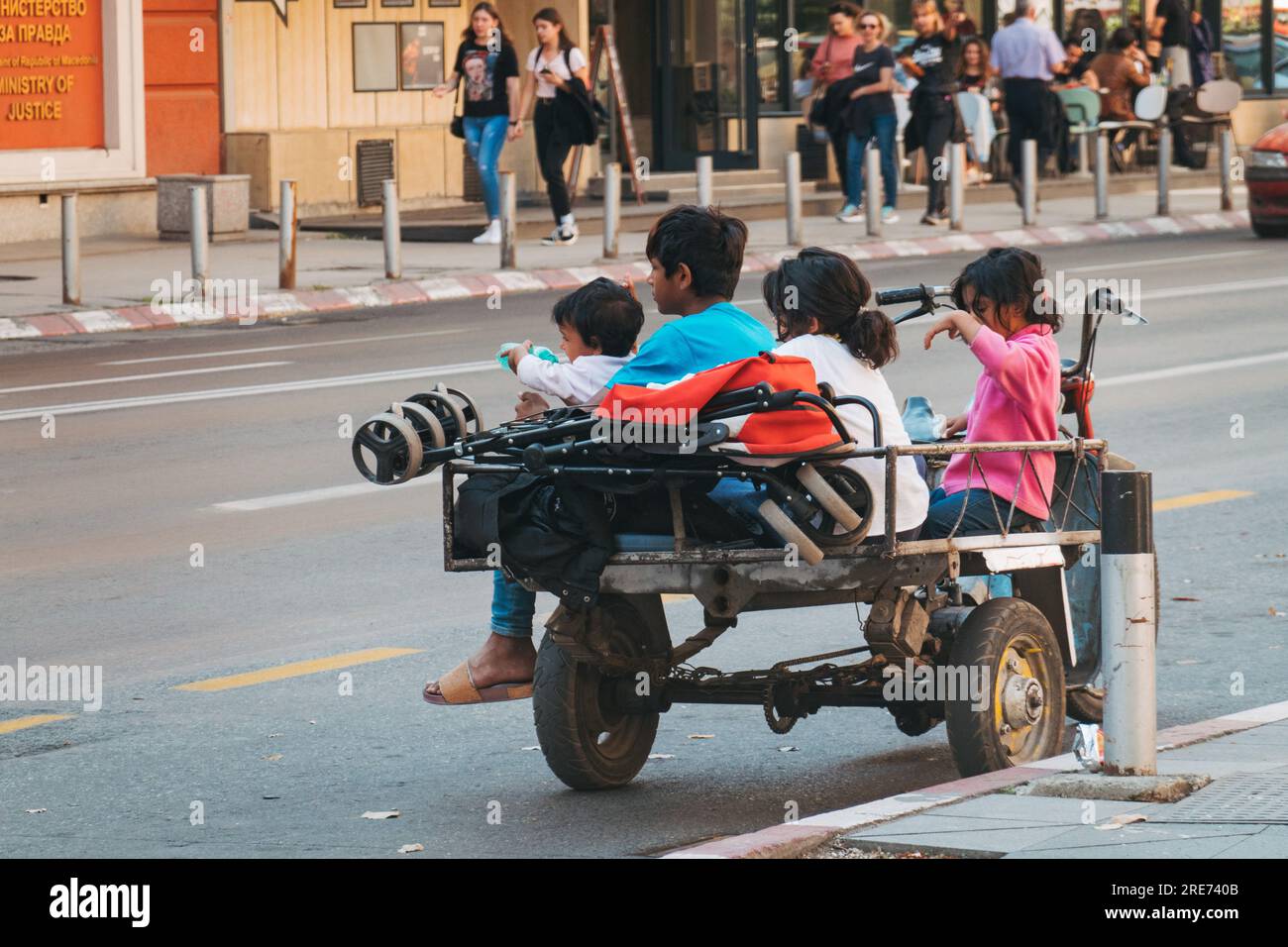 Homeless children sit on the back of a motorized tricycle on a street in Skopje, North Macedonia Stock Photo