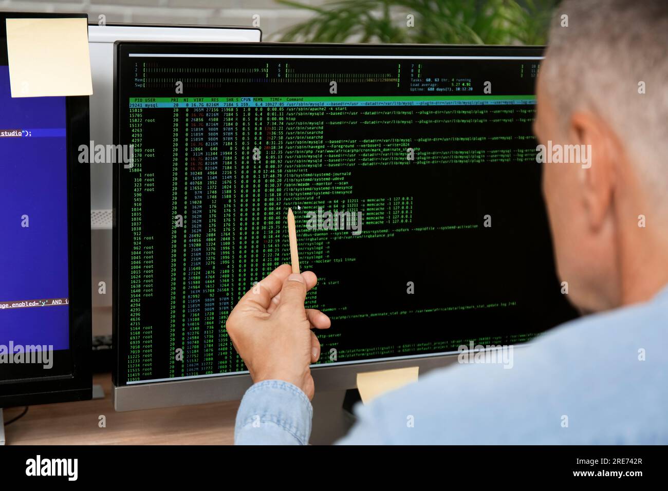 Male programmer pointing at computer monitor with command line ...