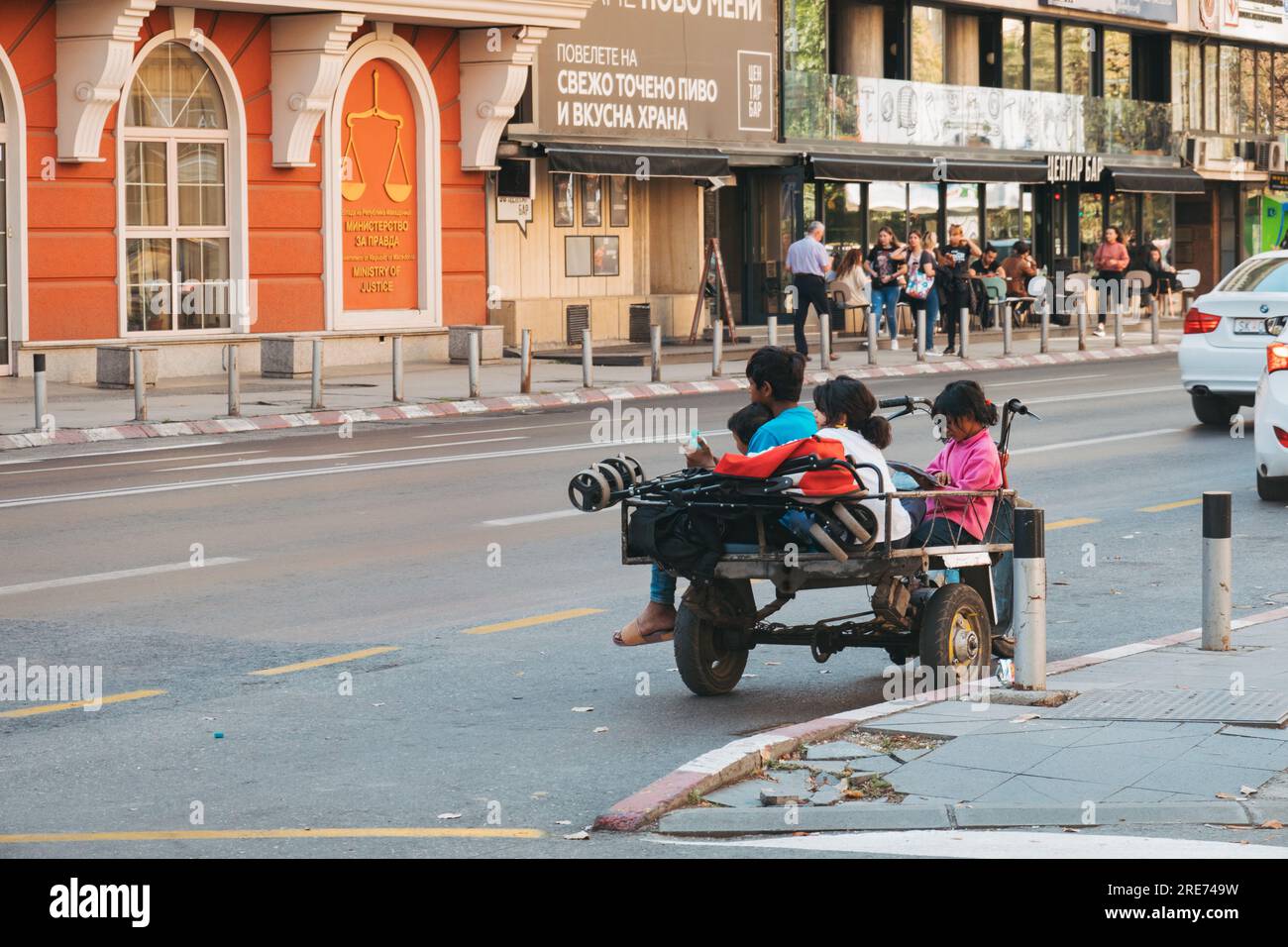 Homeless children sit on the back of a motorized tricycle on a street in Skopje, North Macedonia Stock Photo
