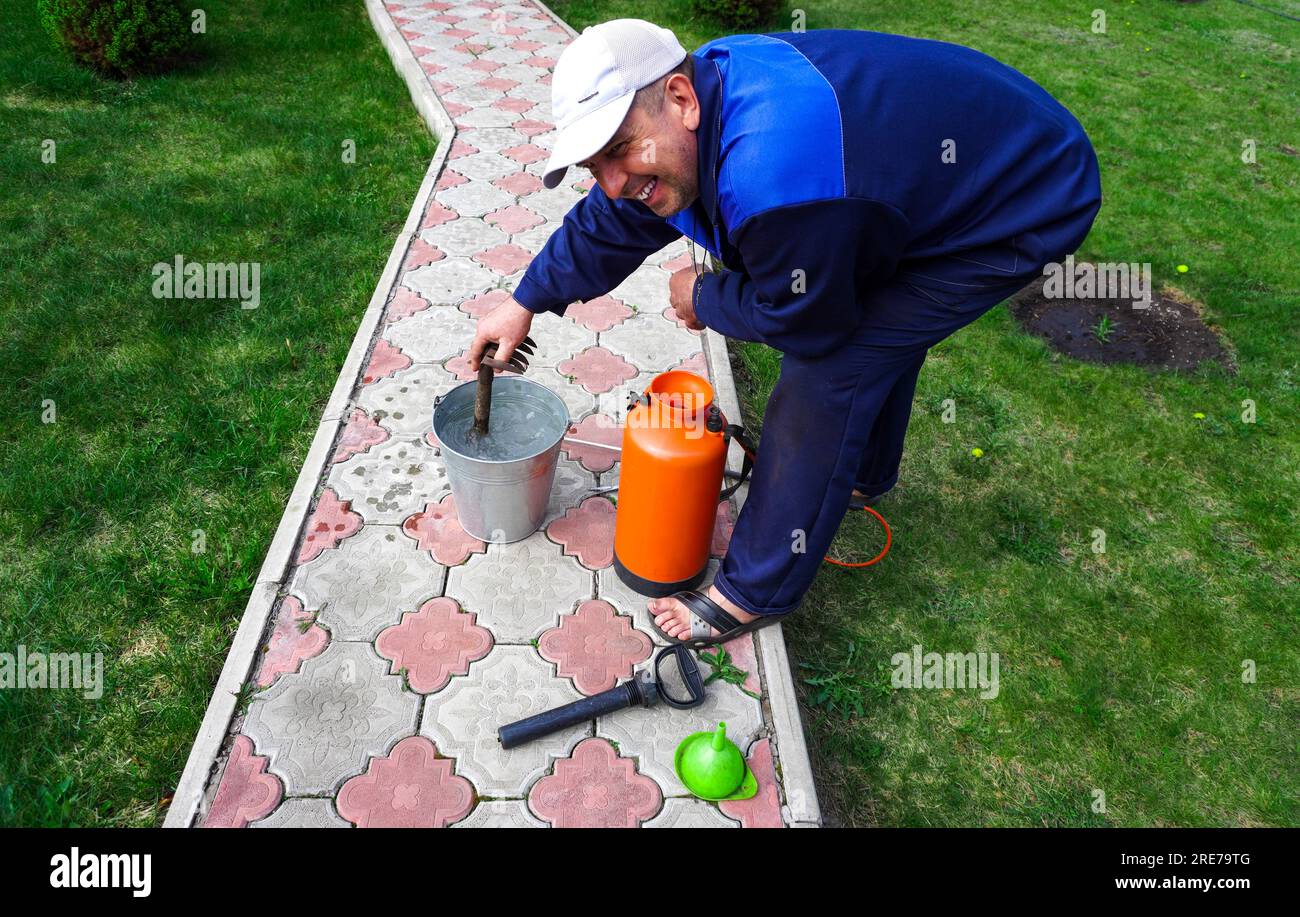 A man works in the garden, spraying weeds from a sprayer Stock Photo ...