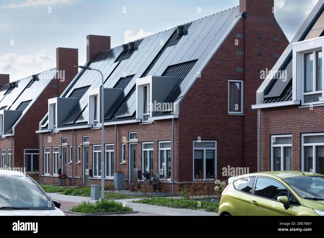 Street with modern social single-family new-build homes with solar panels on roof in the Netherlands. Sustainable energy. Electric power generation Stock Photo