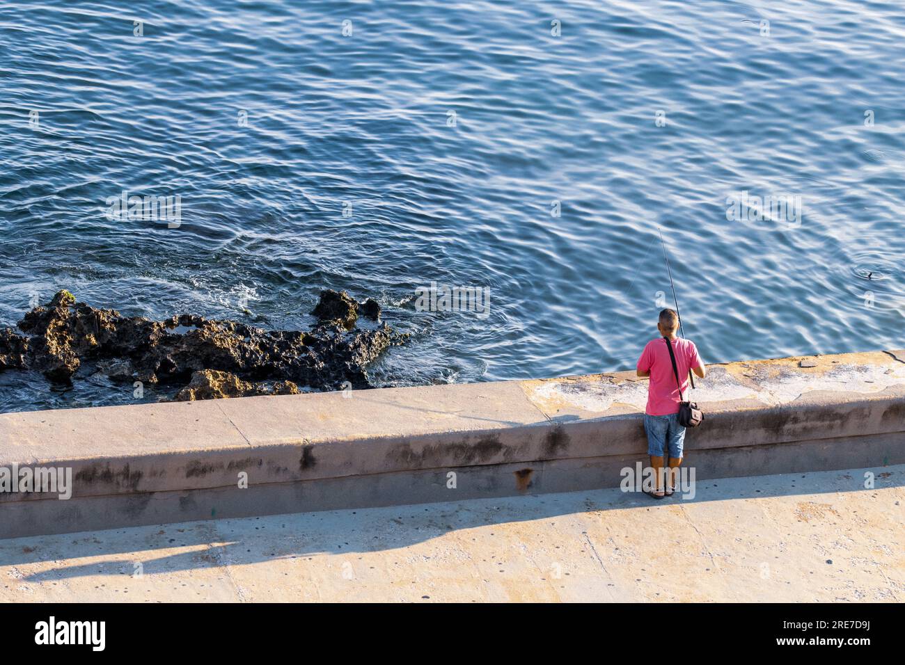 Man fishing waterfront street in La Havana. Malecon man fishing alone ...