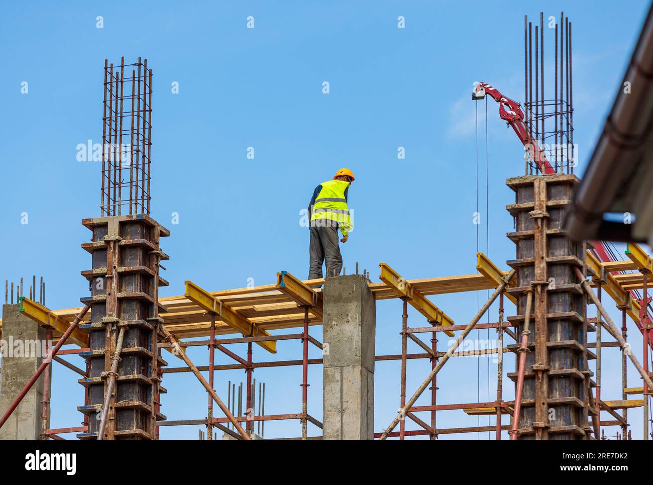 A male construction worker stands on reinforced concrete beams at a ...