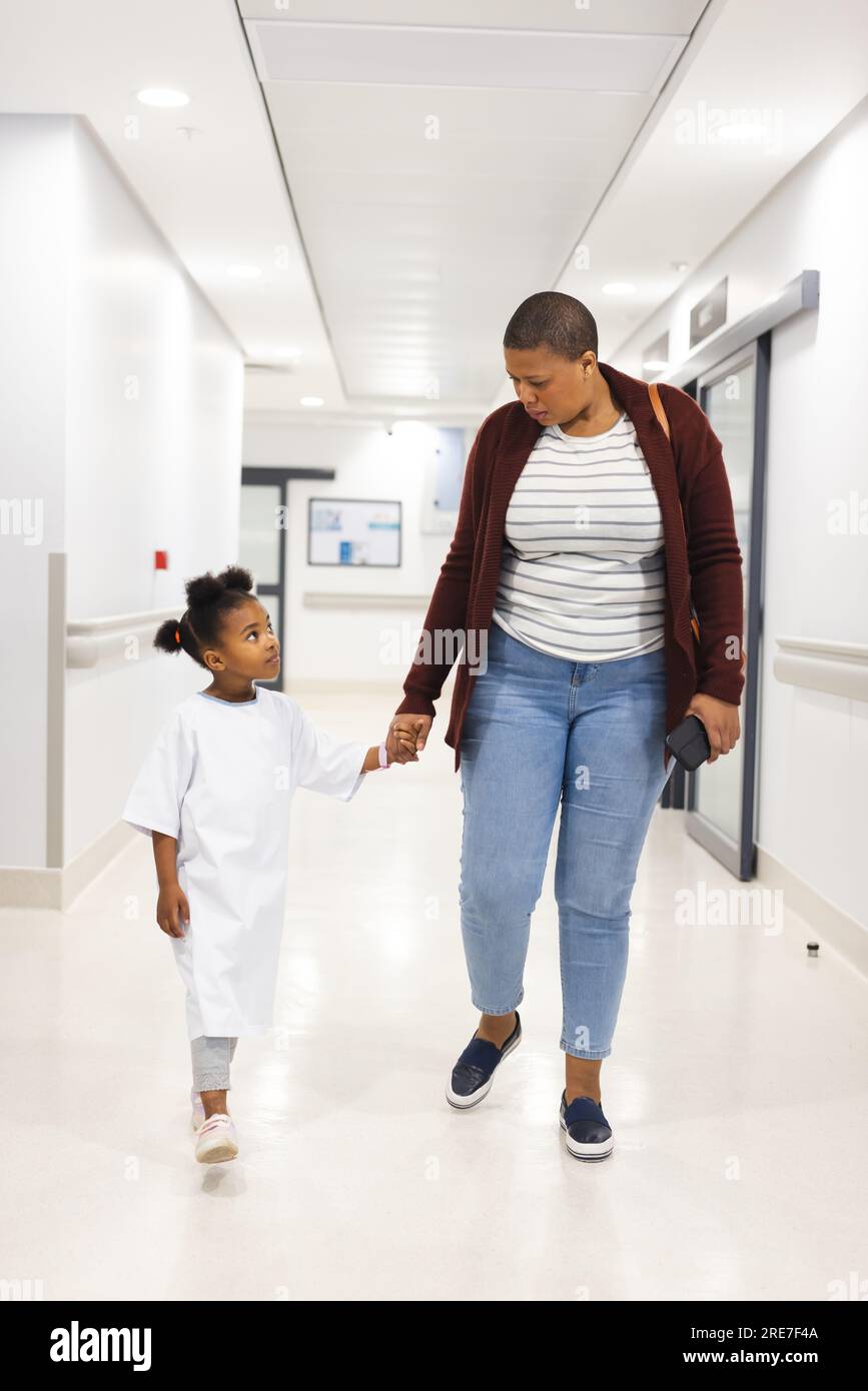 African american girl patient and her mother walking in corridor at hospital Stock Photo