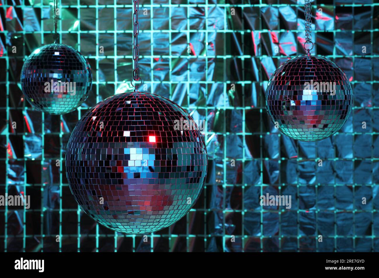 Shiny disco balls against foil party curtain under color lights Stock