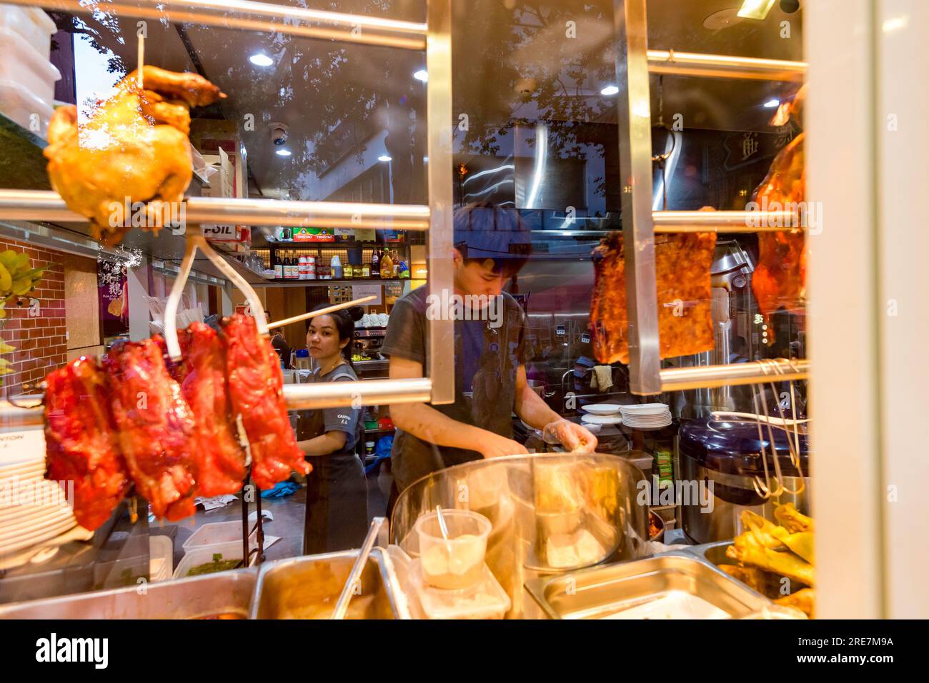 People working in a Chinese restaurant with food in the window during Lunar (Chinese) New Year in Sydney's Dixon Street (China Town) in Australia Stock Photo