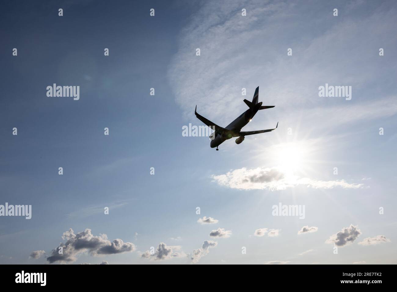 A plane lands at Duesseldorf International Airport, north rhine-westphalia, with the sun and blue sky in the background. Stock Photo