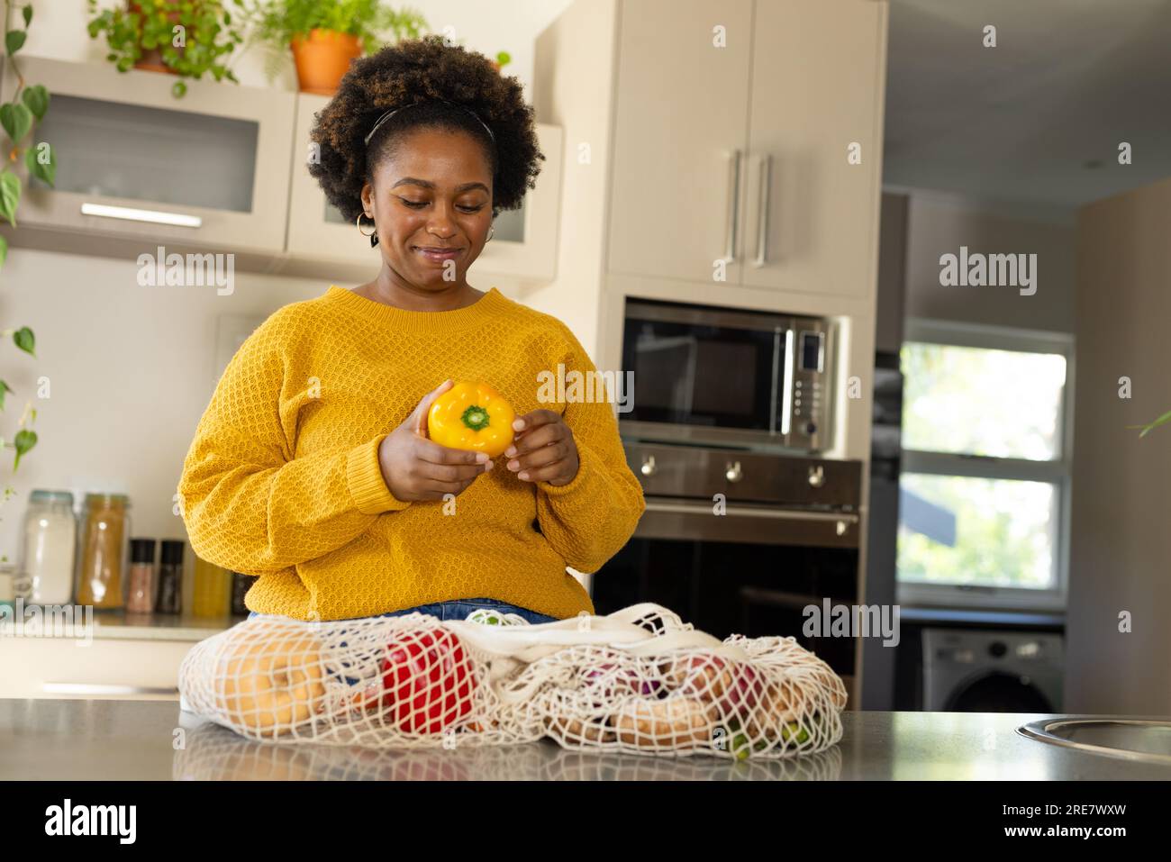 Happy plus size african american woman unpacking groceries in kitchen Stock Photo