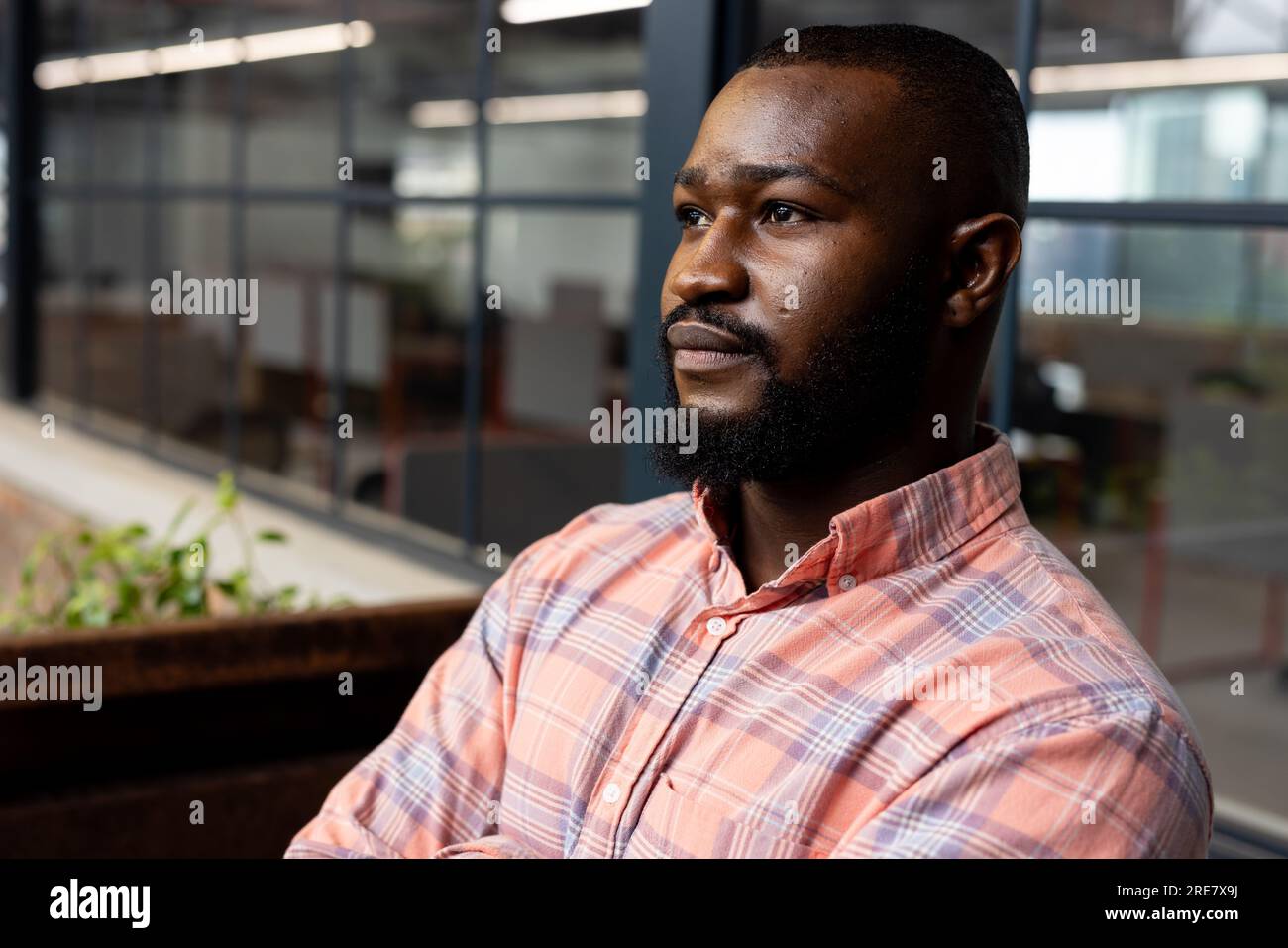 Thoughtful african american businessman looking away standing at modern office Stock Photo