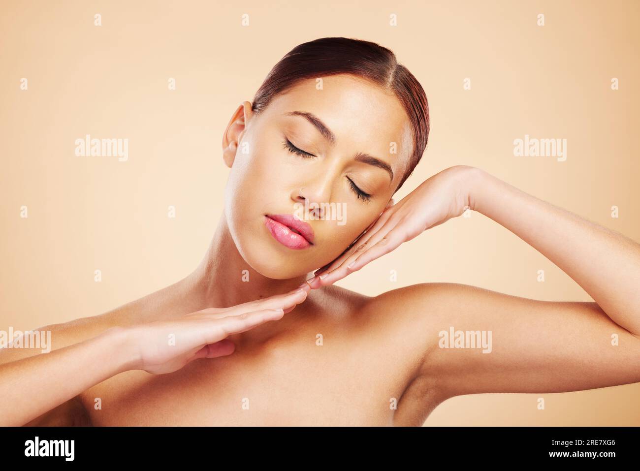Face, calm or woman with natural beauty in studio isolated on brown background for wellness or glow. Skin care shine, hands or zen Brazilian girl Stock Photo