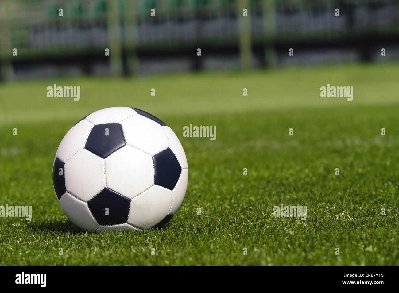 Football Ball on the Grassy Turf of the Stadium. Soccer Ball on Grass Soccer Field. Sports Pitch in Blurred Background Stock Photo