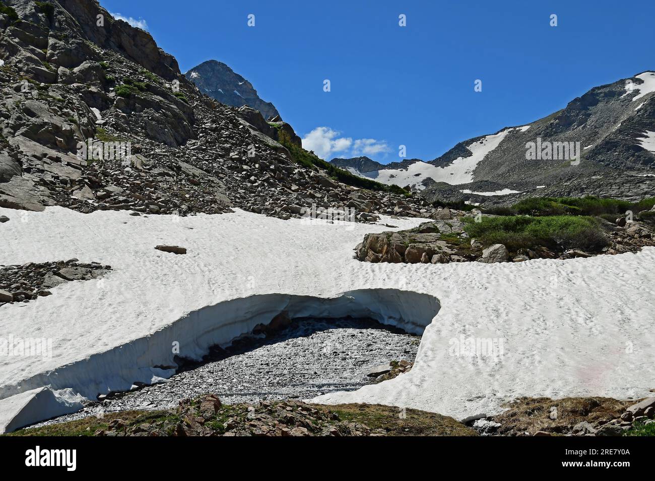 picturesque   snow field,  creek,  and peaks on a sunny summer day along the hiking trail to blue lake, in the indian peaks wilderness area, colorado Stock Photo