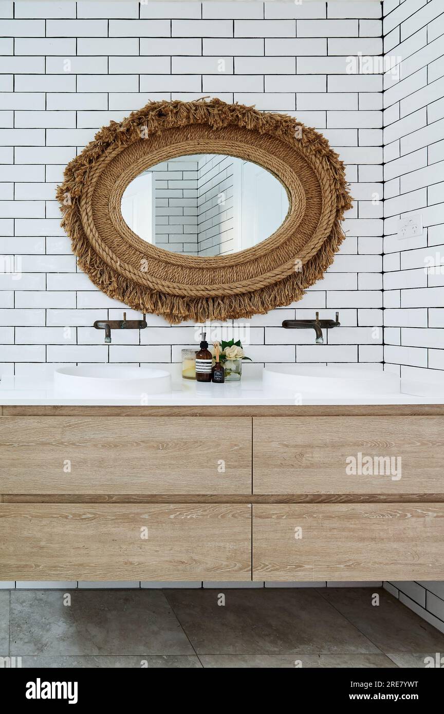 White tiled bathroom with rustic oval mirror and wooden vanity Stock Photo