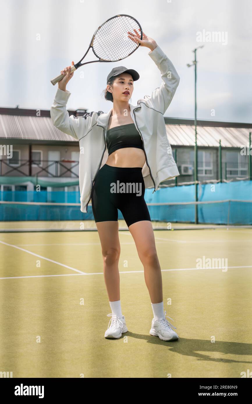 beautiful tennis player in active wear and cap posing with tennis ...