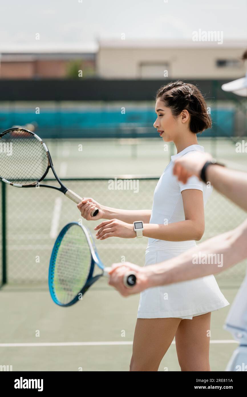 woman in tennis skirt practicing on tennis court, holding racket, boyfriend and girlfriend, sport Stock Photo