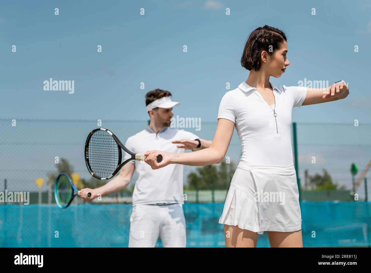 woman in tennis skirt holding racket near boyfriend on court, summer sport, couple, leisure Stock Photo