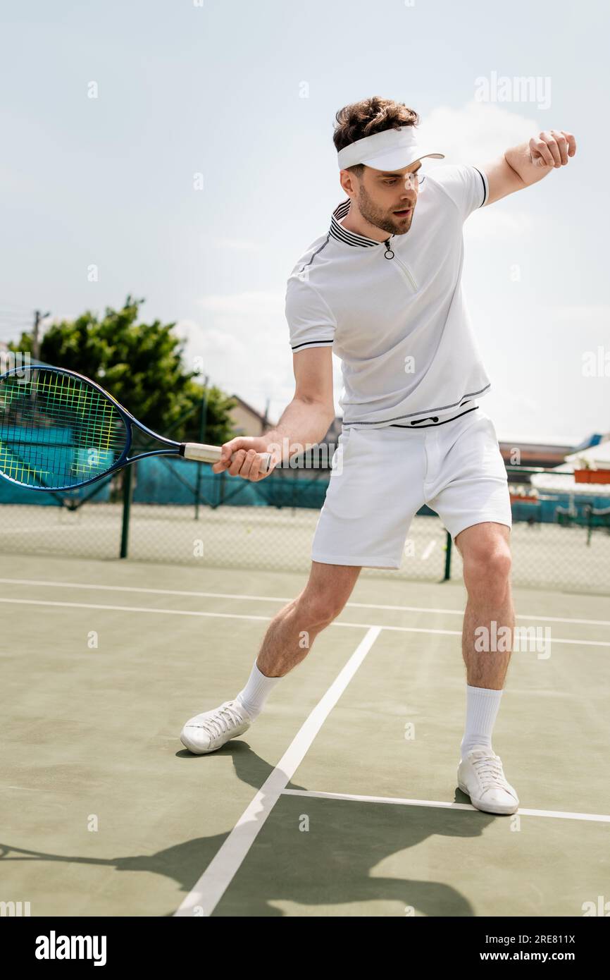 sporty man in sports visor holding racket and playing tennis on court,  training and motivation Stock Photo - Alamy