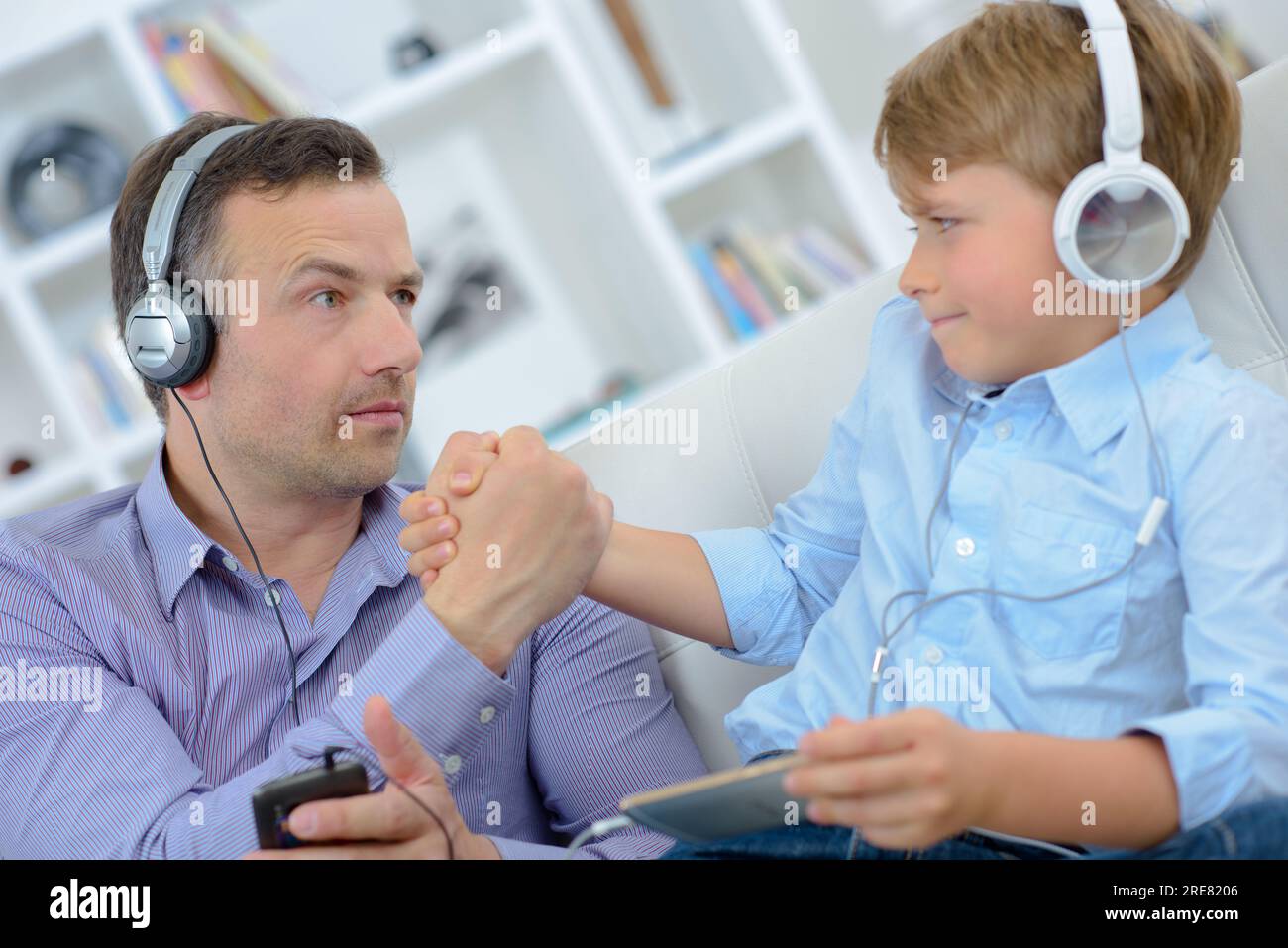 Father and son wearing headphones, arm wrestling Stock Photo Alamy