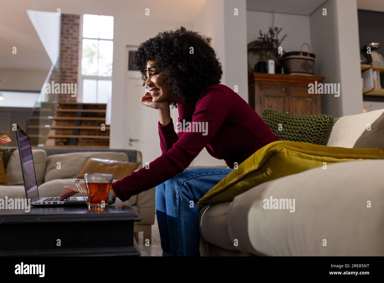 Happy biracial woman using laptop at home Stock Photo - Alamy