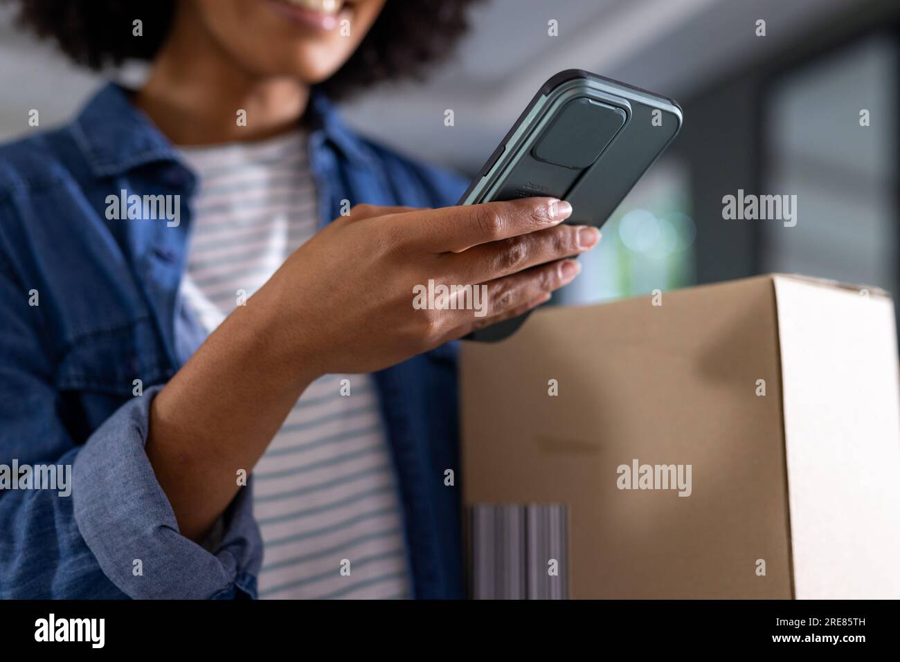 Happy biracial woman using smartphone at home Stock Photo