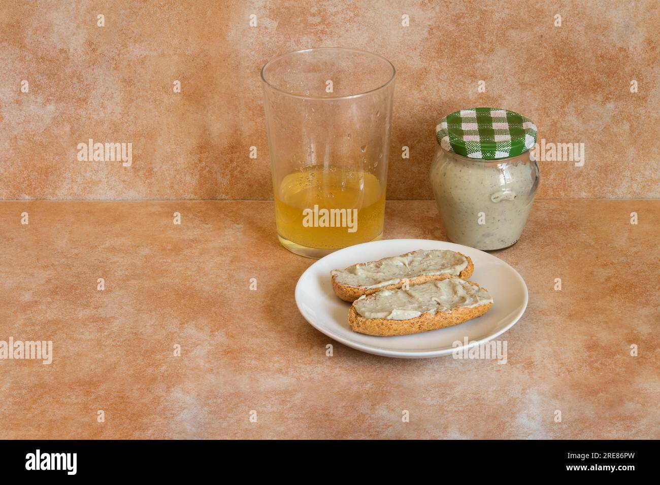 wo toasted wholemeal rolls with cabrales cream and cider on a small plate, accompanied by a glass of cider with a shot and a closed transparent jar of Stock Photo