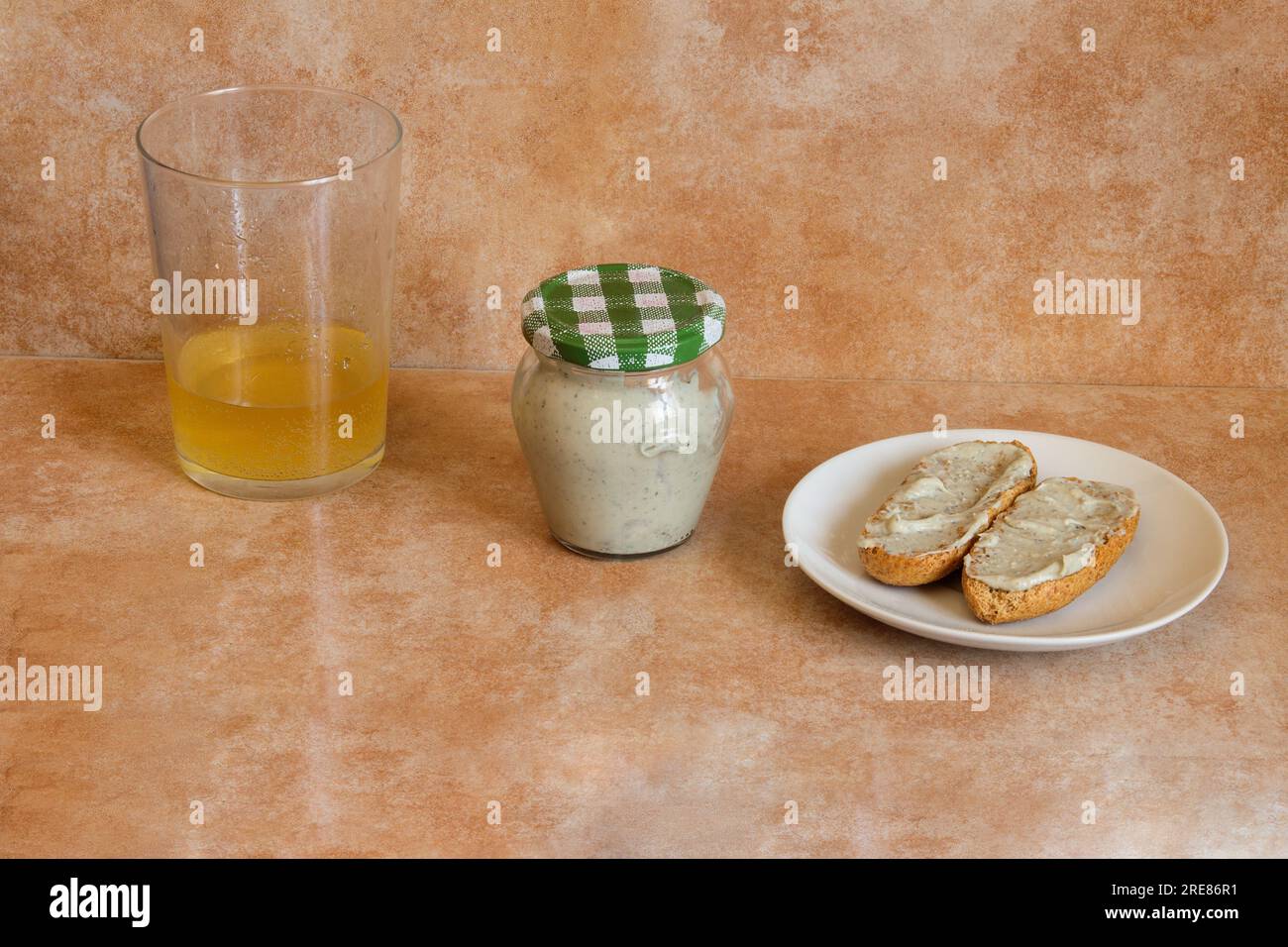 Creamy Cabrales cheese in a small transparent jar, paired with a shot in a cider glass and a toasted whole wheat bread topped with Cabrales cheese. Tr Stock Photo