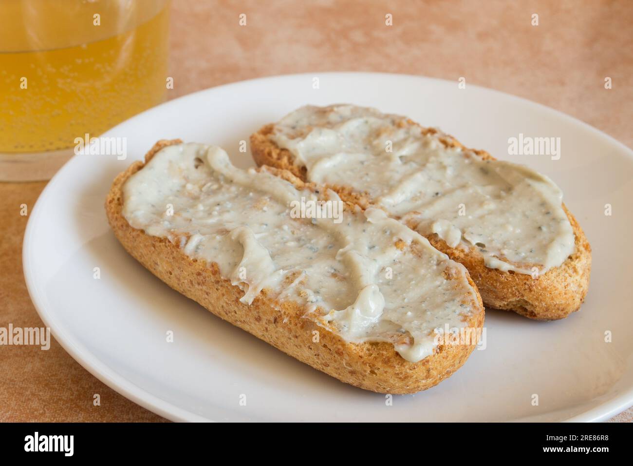 Close-up of Cabrales cream on toasted wholemeal bread with a shot of cider in the background. Traditional Spanish recipes and blue cheese. Stock Photo