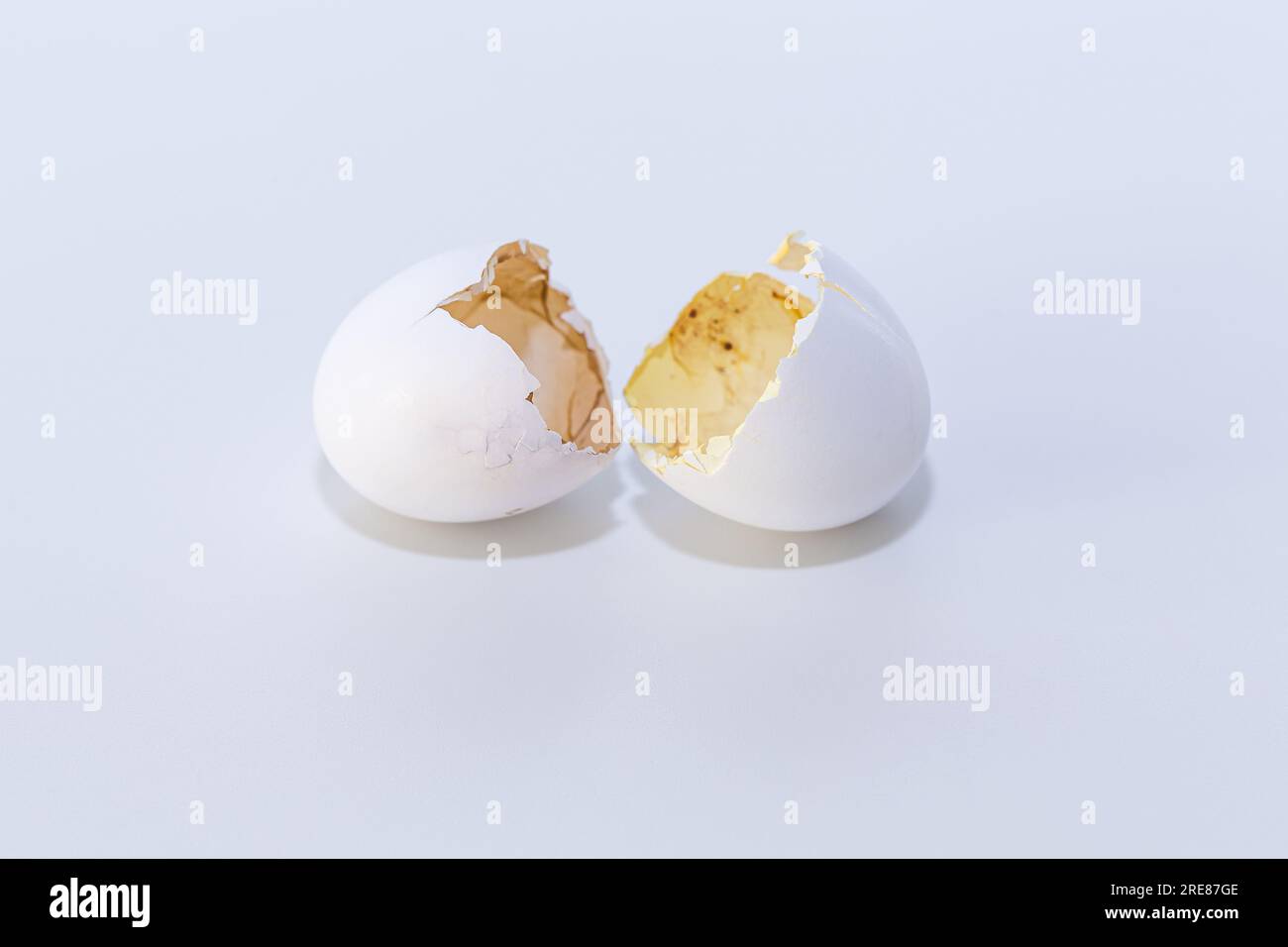 Broken white eggshell on clean bright background representing new life and fresh start. Stock Photo