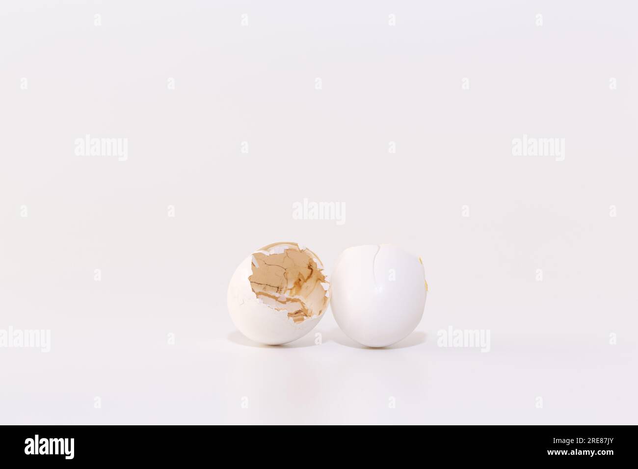 Broken eggshells showing a brown egg inside on white background representing growth concept. Stock Photo