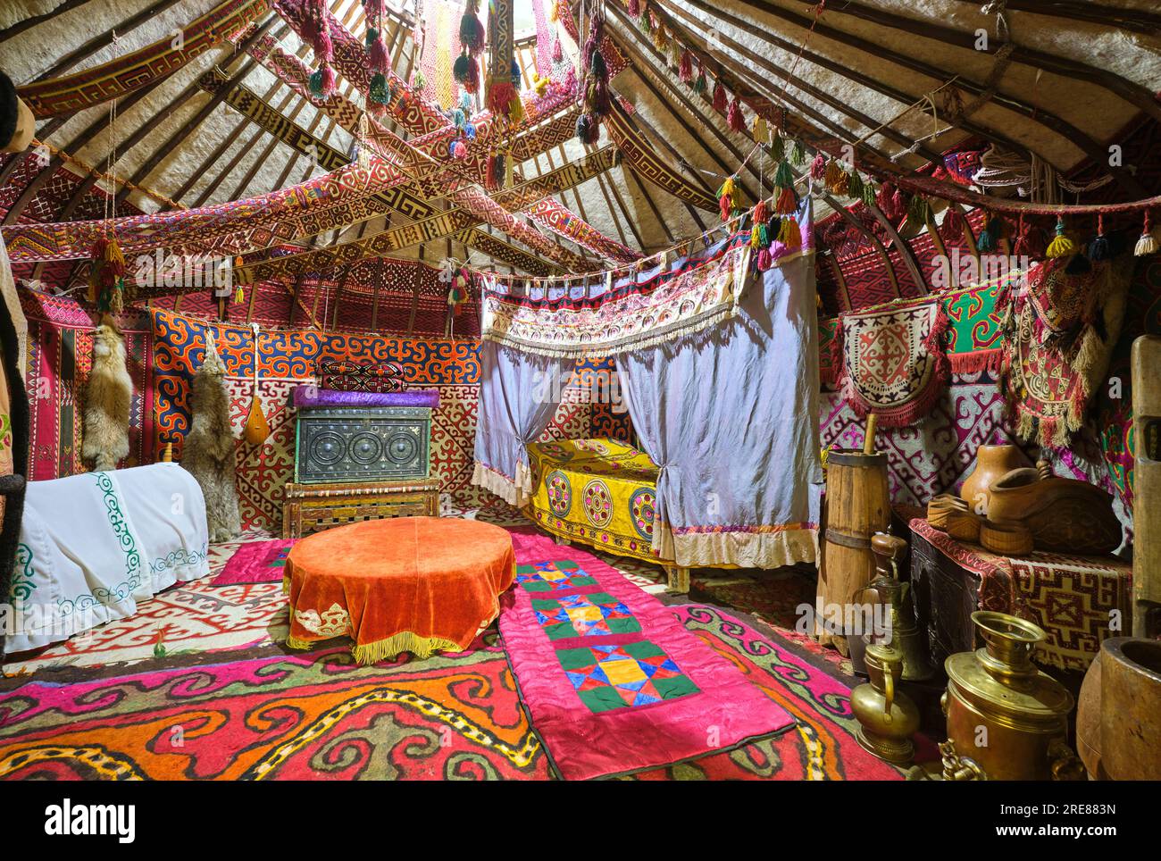 View inside a typical yurt tent, home, details of rich, colorful fabrics, textiles, rugs, furniture. At the South Kazakhstan Regional Historical Museu Stock Photo