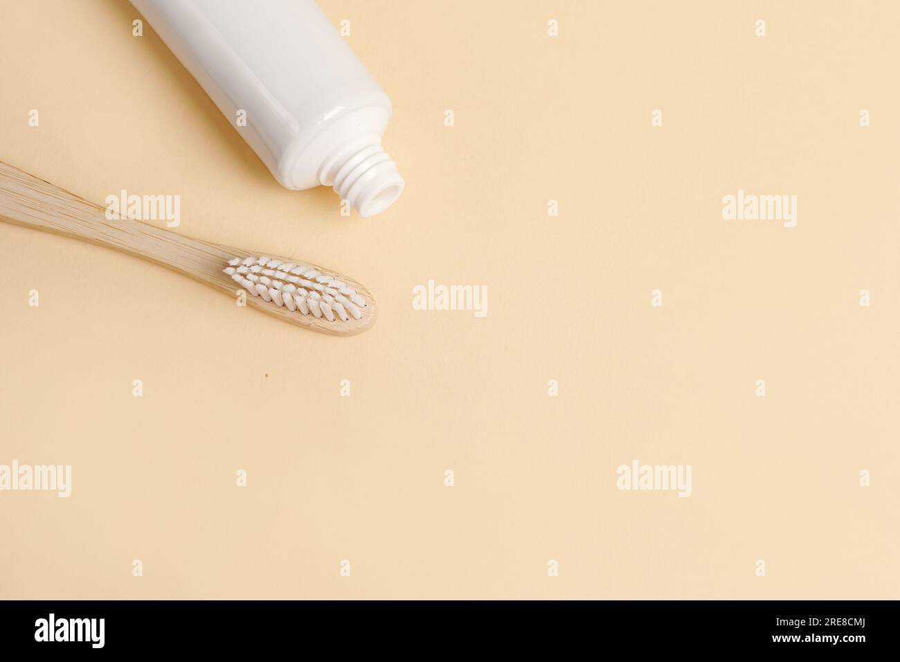 Blank white tube of toothpaste and wood brush on beige background, copy ...