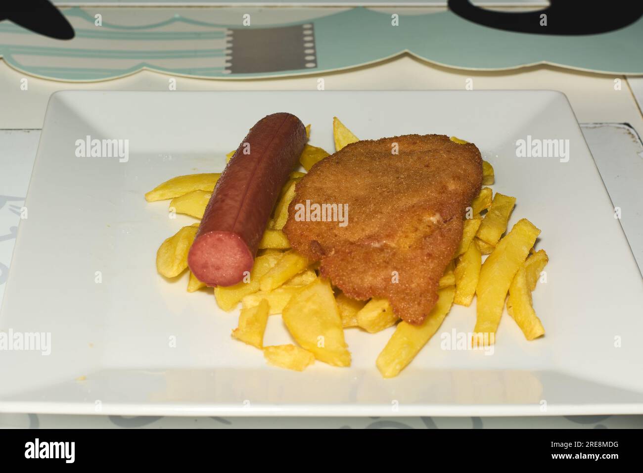 Children's meal plate consisting of fries, half a sausage and a scallop Stock Photo