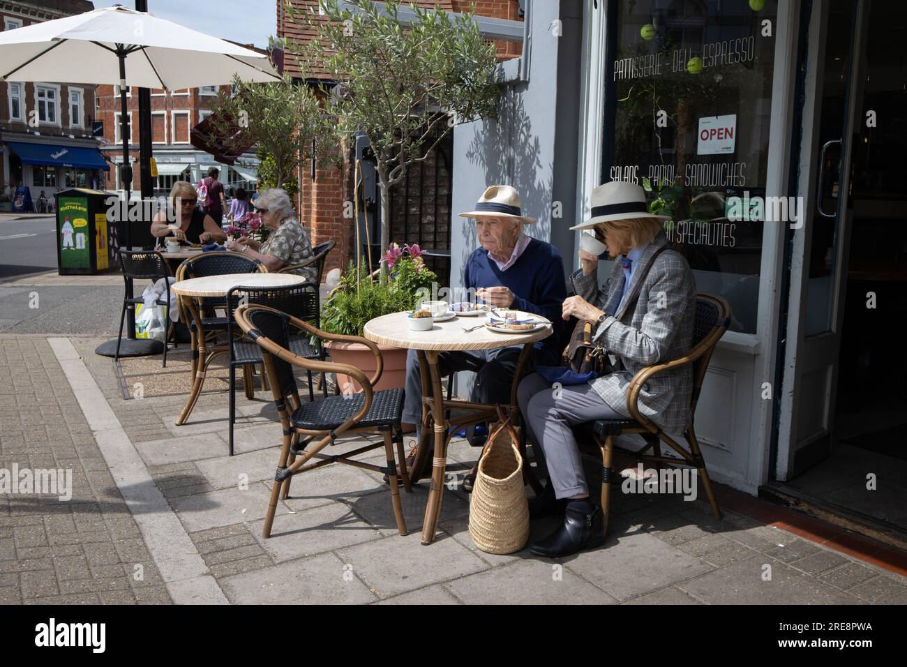 Retired couple wearing Panama Straw hats enjoy lunch in a café along Wimbledon Village High Street, London SW19, England, UK Stock Photo