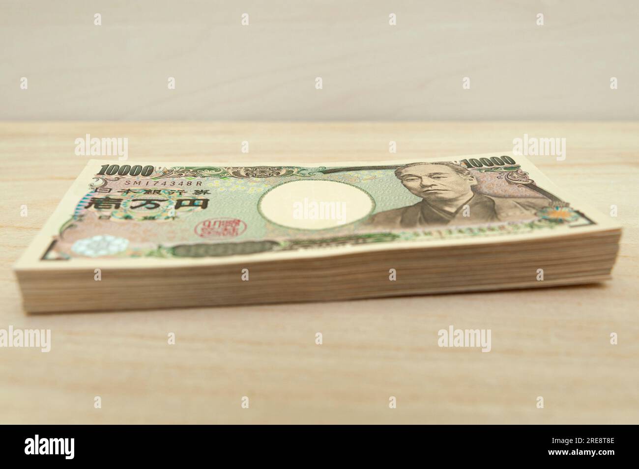 Ten thousand yen (10,000 yen) banknotes stacked. Japanese money. Paper money. isolated on wooden table. Side view. Stock Photo