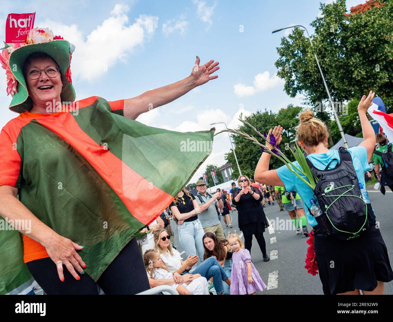 July 21, 2023, Nijmegen, Netherlands: A woman wearing the colors of this event is seen cheering the walkers. Since it is the world's biggest multi-day walking event, The International Four Days Marches (in Dutch 'De Vierdaagse') is seen as the prime example of sportsmanship and international bonding between military servicemen, women and civilians from many different countries. This year, it was the 105 edition and the official amount of walkers registered was 43,363 from 77 countries. Participants can choose to walk 30km, 40km, or 50km per day. On the last day, 39,019 walkers crossed the fi Stock Photo