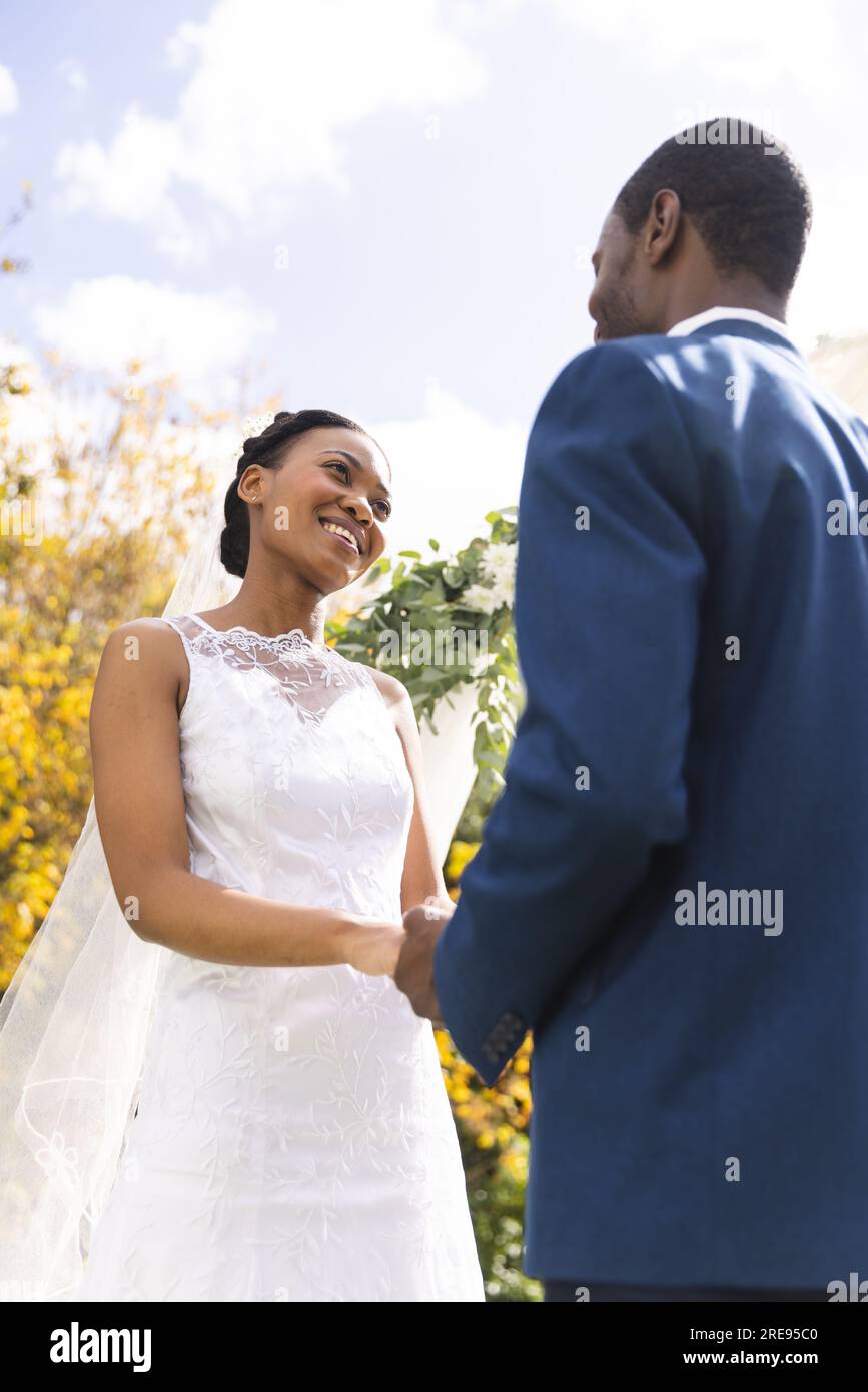 Happy african american bride and groom holding hands at wedding ...