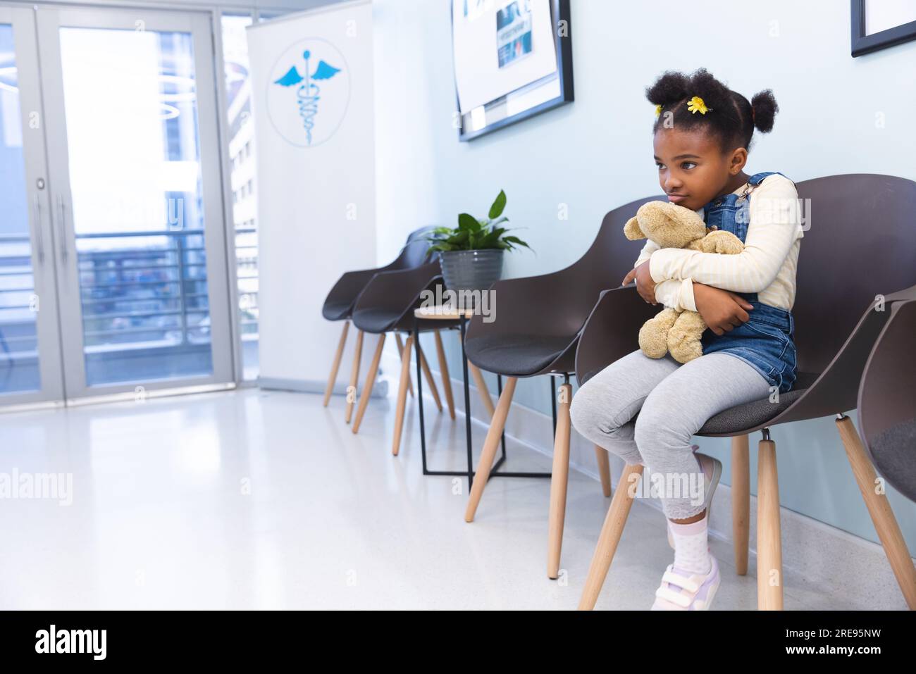 african-american-girl-patient-sitting-in-waiting-room-embracing-teddy