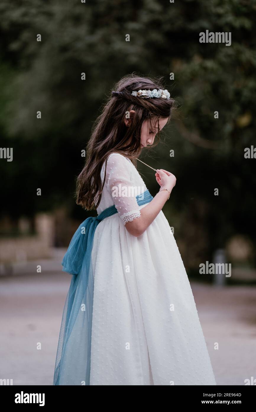 Side view of teen girl in white fancy dress and with hair band standing ...