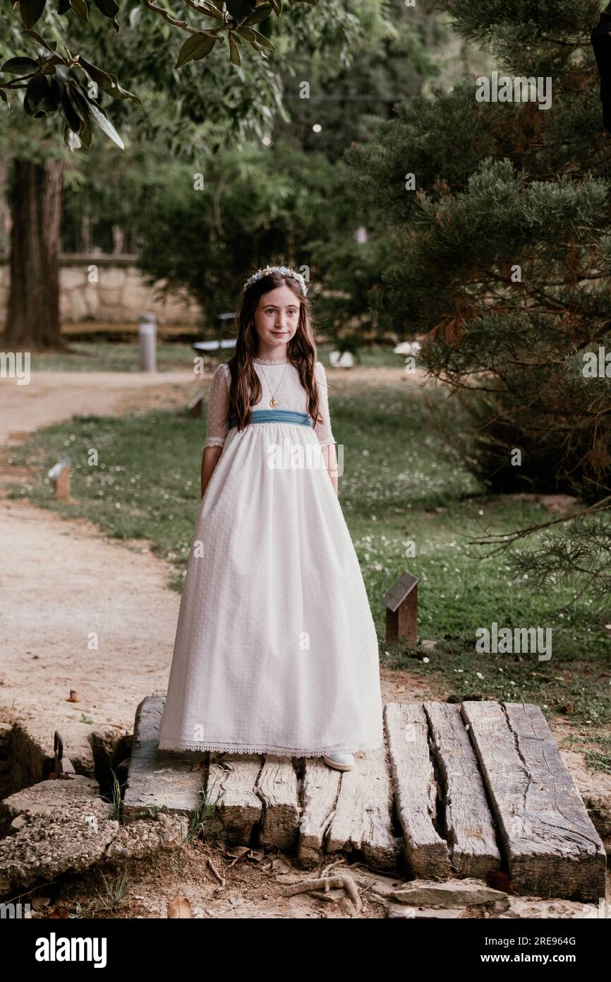 Full body of calm teen girl in elegant white fancy dress standing in park near green trees and looking away Stock Photo Alamy